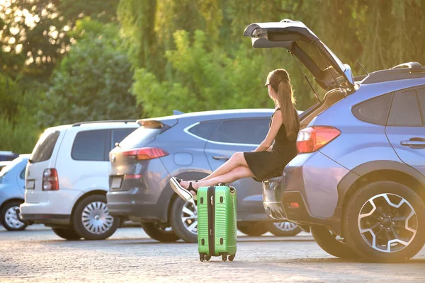 Una joven con una maleta esperando cerca de su coche. Concepto de viajes y vacaciones — Foto de Stock
