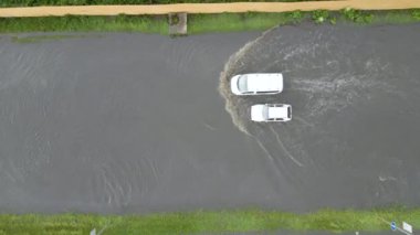 Şiddetli yağmurdan sonra sel basmış caddede giden arabalarla şehir trafiğinin hava görüntüsü. Yol drenaj sistemi ile ilgili sorunlar