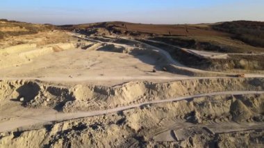 Kazı makineleri ve çöp kamyonlarıyla inşaat endüstrisi için kumtaşı malzemelerinden oluşan açık maden manzarası. Madencilik ve kullanışlı mineral üretiminde ağır ekipman