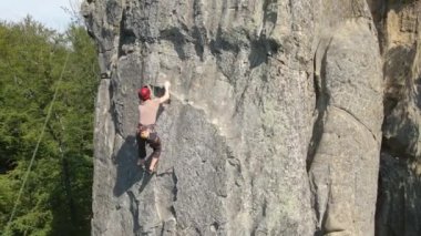 Kararlı dağcı kayalık dağın dik duvarına tırmanıyor. Sporcu zor yolu aştı. Ekstrem sporlar ve kaya tırmanışı hobileri.