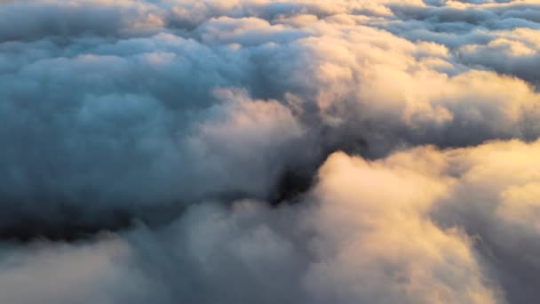 Reveal footage of aerial view from above at high altitude of dense puffy cumulus clouds flying in evening. Amazing sunset from airplane window point of view — Stockvideo