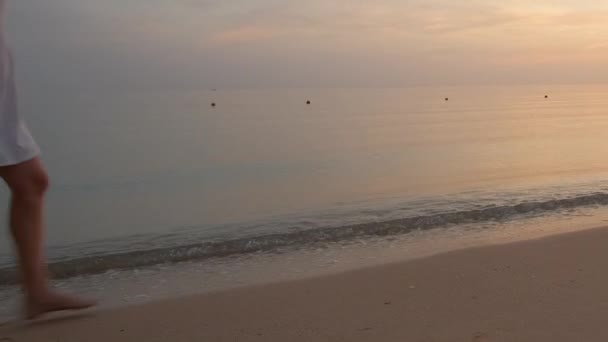 海辺で一人で砂浜を歩いている若い女性は暖かい熱帯夜を楽しんでいます — ストック動画