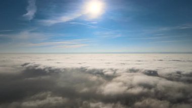 Güneşli bir günde, yeryüzünün yüksek irtifasından beyaz kabarık kümülüs bulutlarıyla kaplı hava manzarası.