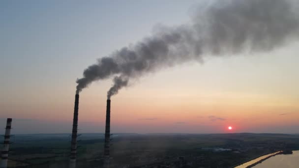 Letecký pohled na vysoké trubky uhelné elektrárny s černým kouřem, který se při západu slunce pohybuje vzhůru znečišťující atmosférou. Výroba elektrické energie s koncepcí fosilních paliv