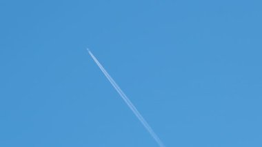 Mesafeli yolcu jet uçağı açık mavi gökyüzünde yüksek irtifada uçarken ardında beyaz duman izi bırakıyor. Hava taşımacılığı kavramı