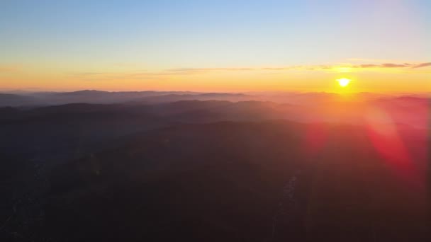 Widok z lotu ptaka na ciemne górskie wzgórza z jasnymi promieniami słońca o zachodzie słońca. Hazy szczyty i zamglone doliny w godzinach wieczornych — Wideo stockowe