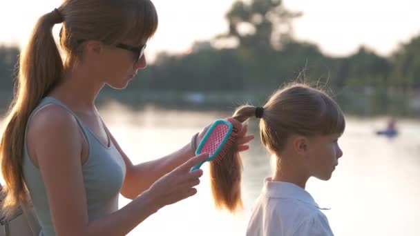 Mãe pentear seu cabelo filha com uma escova ao ar livre no parque de verão — Vídeo de Stock