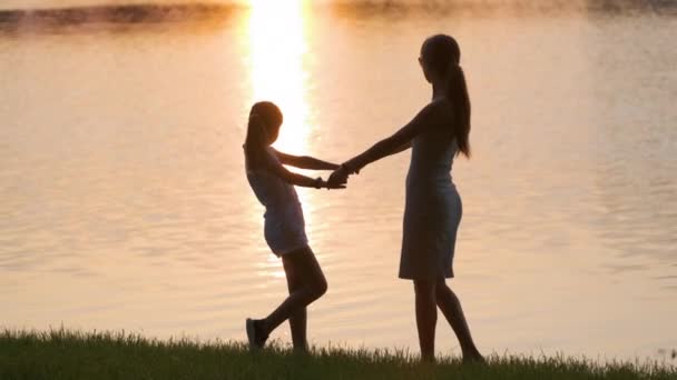 夕方には夏の公園で楽しい時間を楽しむ手を携えて一緒に立って幸せな母親と娘。家族の愛と関係の概念 — ストック動画