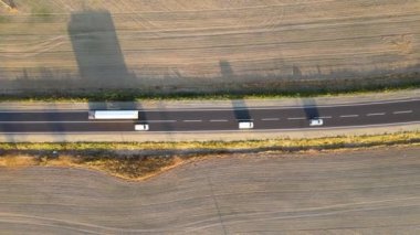 Gün batımında hızlı giden arabalarla şehirlerarası yol manzarası. Akşamları otoban trafiğinin insansız hava aracı görüntüsü