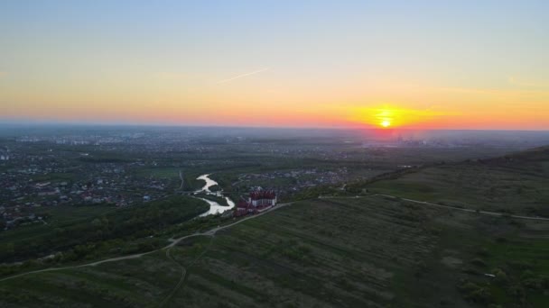 Aerial landscape view of green cultivated agricultural fields with growing crops and distant village houses on bright summer evening — Vídeo de Stock