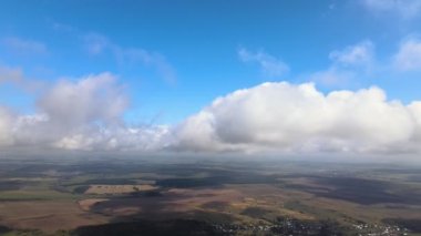 Dünya 'nın yüksek irtifasındaki uçak penceresinden hava manzarası beyaz kabarık kümülüs bulutlarıyla kaplı.