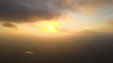 Gün batımında yağmur fırtınasından önce bulutlarla kaplı uzak şehrin yüksek irtifasından gelen hava manzarası. Bulutlu havada uçak manzarası