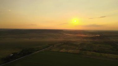 Gün batımında tarlalar arasında hızlı giden arabalarla şehirlerarası yol manzarası. Akşamları otoban trafiğinin insansız hava aracı görüntüsü