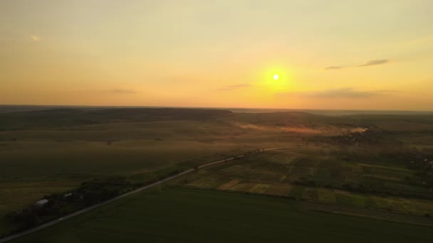 Luftaufnahme einer Überlandstraße mit schnell fahrenden Autos zwischen Feldern bei Sonnenuntergang. Draufsicht von der Drohne auf den Autobahnverkehr am Abend — Stockvideo
