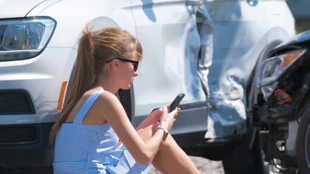 Stressed driver talking on sellphone on roadside near her smashed vehicle calling for emergency service help after car accident. Road safety and insurance concept — Video Stock