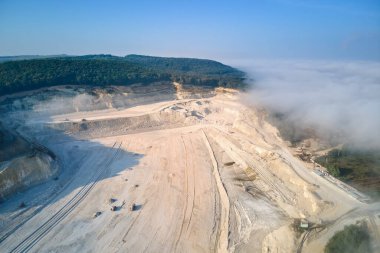Kazı araçları ve çöp kamyonları ile inşaat endüstrisi için kireçtaşı malzemelerinin açık çukur madenciliğinin hava görüntüsü
