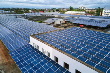 Sanayi binasının çatısına yeşil ekolojik elektrik üretmek için monte edilmiş mavi fotovoltaik panelli güneş enerjisi santralinin hava görüntüsü. Sürdürülebilir enerji konsepti üretimi