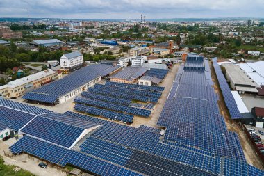 Sanayi binasının çatısına yeşil ekolojik elektrik üretmek için monte edilmiş mavi fotovoltaik panelli güneş enerjisi santralinin hava görüntüsü. Sürdürülebilir enerji konsepti üretimi