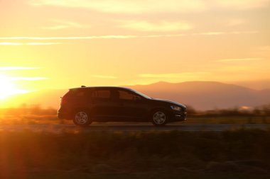 Gün batımında şehir içi yolda hızlı giden bir araba. Akşamları otoyol trafiği