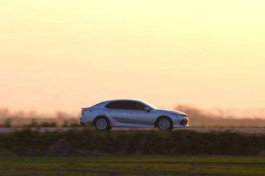 Gün batımında şehir içi yolda hızlı giden bir araba. Akşamları otoyol trafiği