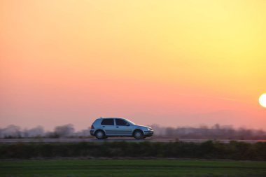 Gün batımında şehir içi yolda hızlı giden bir araba. Akşamları otoyol trafiği
