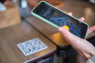 Konuk elin restoranda yemek sipariş ederken çevrimiçi menü için qr kodunu cep telefonuyla taraması