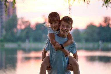 Mutlu kardeşler yaz parkında sevgiyle sarılıyorlar. Küçük çocuklar, erkek ve kız kardeşler dışarıda birbirlerini kucaklıyorlar. Aile sevgisi ve ilişki kavramı