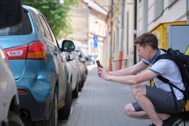 Stresli şoför, trafik kazasından sonra acil servis için sokak kenarındaki çamurluğun cep telefonundaki kamerasıyla fotoğraf çekiyor. Yol güvenliği ve sigorta kavramı