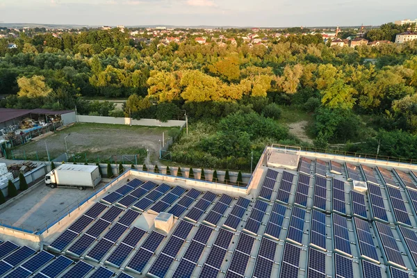 Widok z powietrza niebieskich fotowoltaicznych paneli słonecznych zamontowanych na dachu budynku przemysłowego do produkcji ekologicznej energii elektrycznej. Produkcja koncepcji zrównoważonej energii — Zdjęcie stockowe
