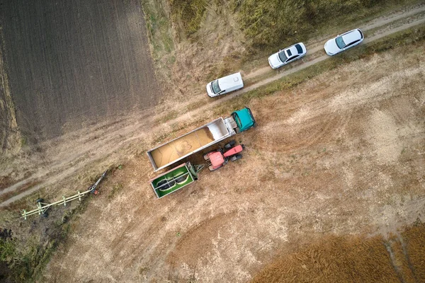 Αεροφωτογραφία του φορτηγού που οδηγεί σε χωματόδρομο μεταξύ αγροτεμαχίων σιταριού που παράγει πολλή σκόνη. Μεταφορά σιτηρών μετά τη συγκομιδή από το θεριστή συνδυασμένης συγκομιδής κατά την περίοδο συγκομιδής — Φωτογραφία Αρχείου