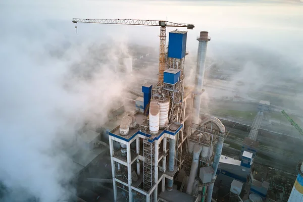 Luftaufnahme einer Zementfabrik mit hoher Betonwerkstruktur und Turmdrehkran an einem nebligen Morgen. Fertigung und globales Branchenkonzept — Stockfoto