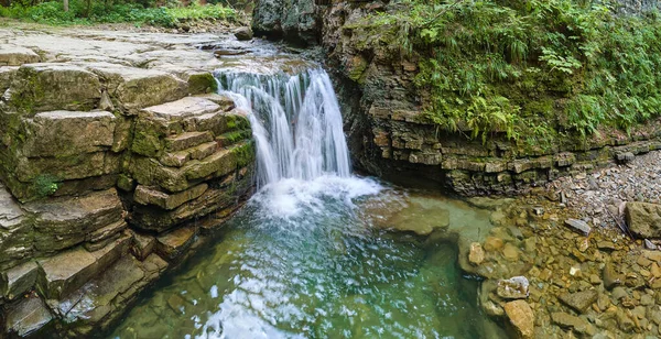 Úžasná krajina krásného vodopádu na horské řece s bílou pěnivou vodou padající z skalnatého útesu v letním deštném pralese — Stock fotografie