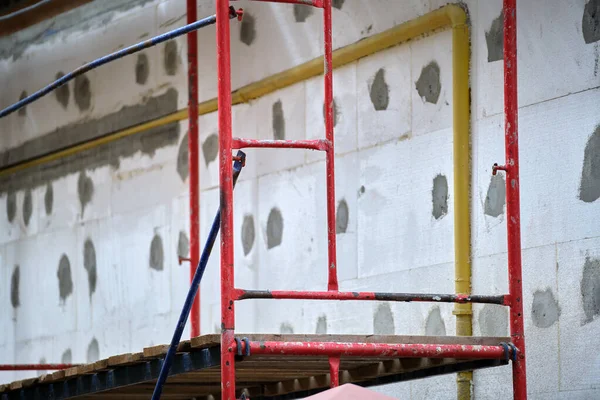 Fasada budynku w trakcie prac remontowych z konstrukcyjną ramą rusztowaniową. Izolacja ścian z arkuszami styropianu dla energooszczędnego domu — Zdjęcie stockowe