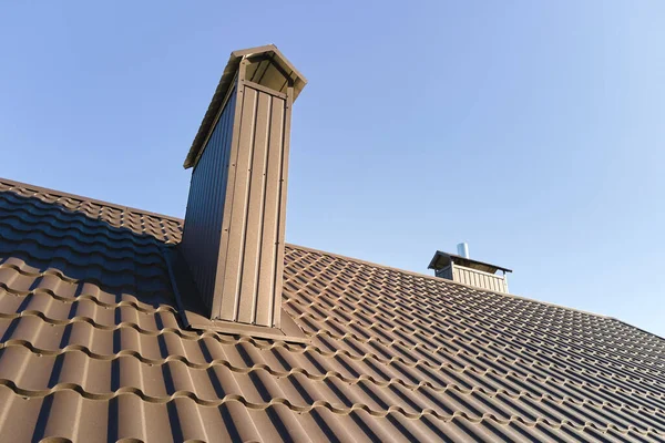 Chimney on house roof top covered with metallic shingles under construction. Tiled covering of building. Real estate development — Stockfoto