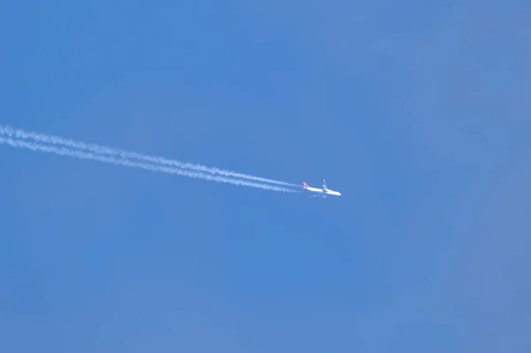 Mesafeli yolcu jet uçağı açık mavi gökyüzünde yüksek irtifada uçarken ardında beyaz duman izi bırakıyor. Hava taşımacılığı kavramı — Stok fotoğraf