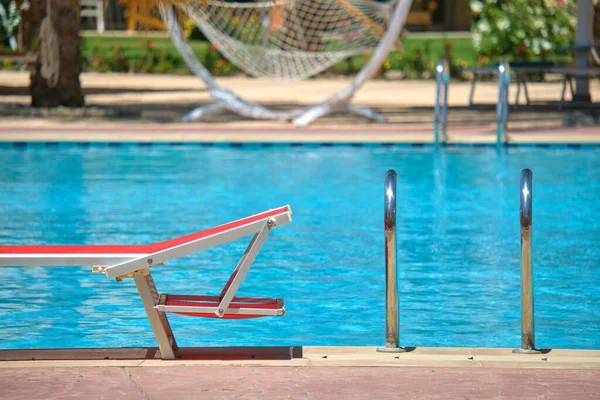 Lege ligstoel aan de rand van het zwembad in het zomerresort. Vakantie en vakantie concept — Stockfoto