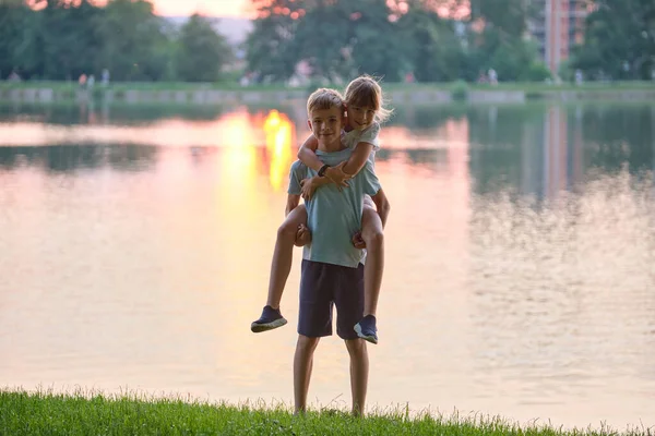 Felices hermanos abrazándose amorosamente en el parque de verano. Niños pequeños hermano y hermana abrazándose al aire libre. Amor familiar y concepto de relación — Foto de Stock