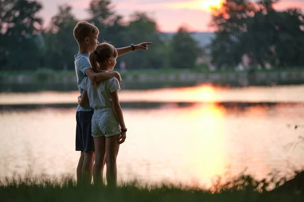 Szczęśliwe rodzeństwo trzymające się razem za ręce w letnim parku. Młode dzieci brat i siostra relaksujący na świeżym powietrzu. Rodzinna miłość i koncepcja relacji — Zdjęcie stockowe