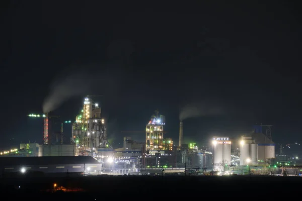 Usine de ciment éclairée avec structure d'usine élevée et grues à tour dans la zone de production industrielle la nuit. Fabrication et concept d'industrie mondiale — Photo