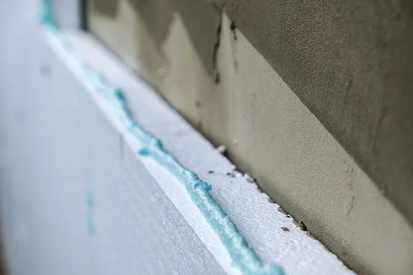 Installation of styrofoam insulation sheets on house facade wall for thermal protection