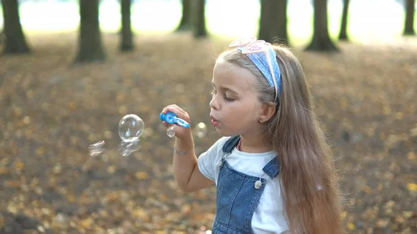 Petite fille heureuse enfant soufflant des bulles de savon à l'extérieur dans le parc d'été — Photo