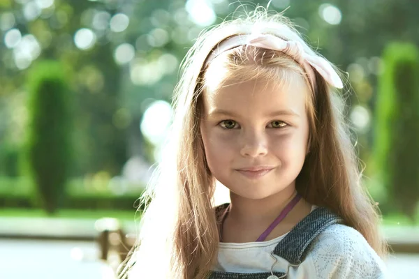 Portret ślicznej dziewczynki stojącej w letnim parku patrzącej w kamerę uśmiechniętej szczęśliwie — Zdjęcie stockowe