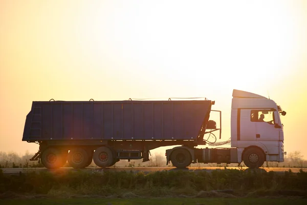 Semi-vrachtwagen met kipwagen die 's avonds zand vervoert uit steengroeve en over de snelweg vervoert. Levering transport en logistiek concept — Stockfoto