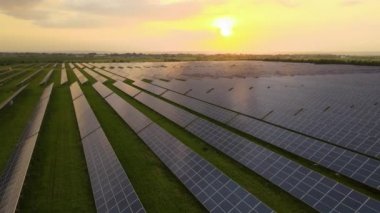 Günbatımında temiz elektrik enerjisi üretmek için birçok sıra güneş fotovoltaik paneli bulunan sürdürülebilir büyük elektrik santralinin havadan görünüşü. Sıfır emisyon kavramı ile yenilenebilir elektrik