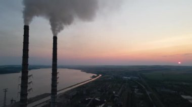 Kara dumanlı yüksek boruların hava görüntüsü gün batımında atmosferi kirletiyor. Fosil yakıt kavramına sahip elektrik enerjisi üretimi