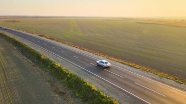 Gün batımında hızlı giden arabalarla şehirlerarası yol manzarası. Akşamları otoban trafiğinin insansız hava aracı görüntüsü