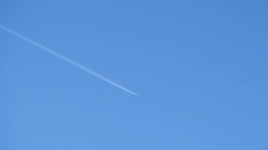 Mesafeli yolcu jet uçağı açık mavi gökyüzünde yüksek irtifada uçarken ardında beyaz duman izi bırakıyor. Hava taşımacılığı kavramı