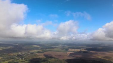 Dünya 'nın yüksek irtifasındaki uçak penceresinden hava manzarası beyaz kabarık kümülüs bulutlarıyla kaplı.