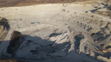Kazı makineleri ve çöp kamyonlarıyla inşaat endüstrisi için kumtaşı malzemelerinden oluşan açık maden manzarası. Madencilik ve kullanışlı mineral üretiminde ağır ekipman