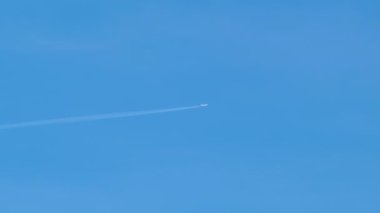 Mesafeli yolcu jet uçağı açık mavi gökyüzünde yüksek irtifada uçarken ardında beyaz duman izi bırakıyor. Hava taşımacılığı kavramı